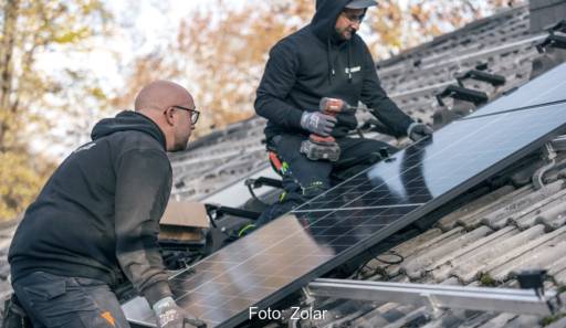 Im Bild zwei Handwerker auf dem Dach mit Solarmodul bei einer Installation vom Solar-Online-Anbieter Zolar.