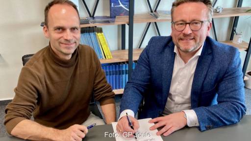 Zwei Männer an einem Tisch, einer unterschreibt auf einem Blatt Papier - Vereinbarung von Gp Joule und Apus zu Betankung von Wasserstoff-Flugzeugen