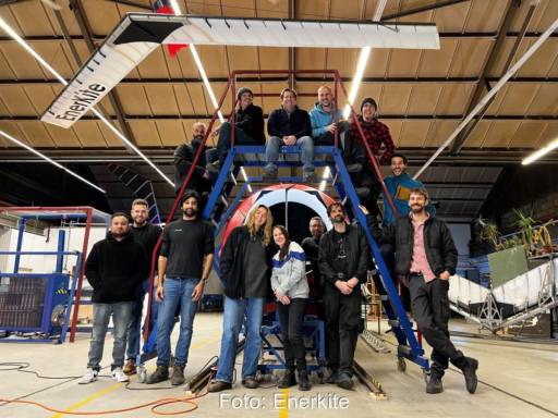 Gruppe von Männern und Frauen auf Leiter in einer Halle, darüber die Flugwindkraft-Anlage von Enerkite.