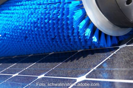 Blaue Bürste auf PV-Modul in Detailaufnahme - Symbol für Reinigung von PV-Freiflächenanlage und Wasseranschluss.