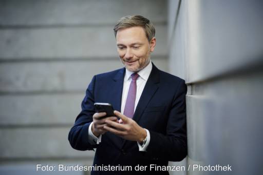 Bundesfinanzminister Lindner lehnt an einer Wand und schaut in sein Smartphone. Er hat das Wachstumschancengesetz vorgeschlagen.