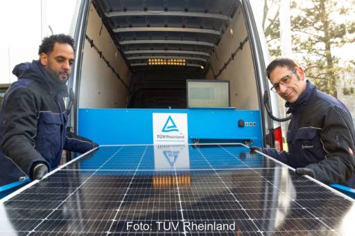 2 Personen prüfen ein Solarmodul an einem Nutzfahrzeug.