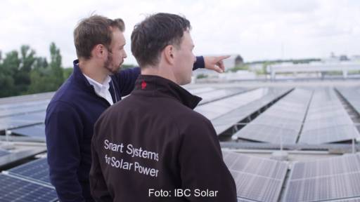 Im Bild zwei Männer, die über eine PV-Anlage schauen. IBC Solar übernimmt Fankhauser Solar in der Schweiz.