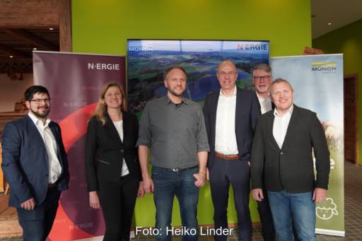 Sechs Personen im Büro vor Firmenaufstellern.