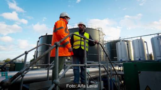 Zwei Männer auf einer Industriebrücke vor großen Behältern einer Biogas-Anlage
