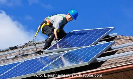 Im Bild ist ein Monteur auf dem Dach bei der Photovoltaik Installation zu sehen, der Betreiber profitiert von der Nullsteuer.
