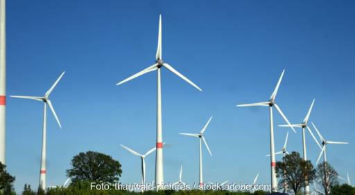 Eine Reihe von Windkraftanlagen vor blauem Himmel.