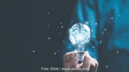 Eine Hand hält eine Glühbirne die grünliches Licht abgibt - Symbolbild für Energieforschungsprogramm