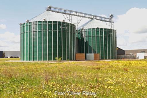 Biogas-Fermenter vor Blumenwiese - Symbolbild für Biomethan.