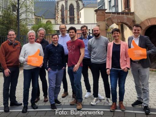 10 Vertreter:innen der Bürgerwerke vor einer historischen Kirche.