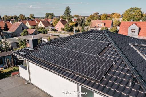 Haus mit schwarzem Schrägdach und Solarmodulen.