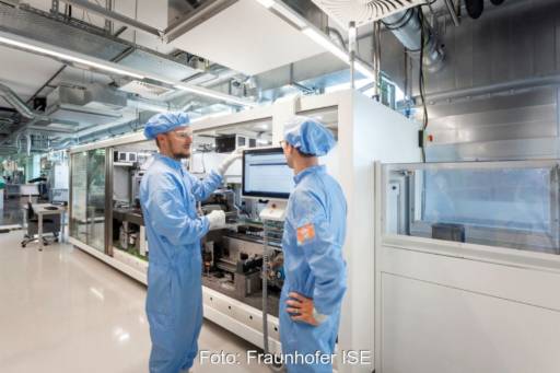 Zwei Männer in blauer Schutzkleidung vor einer Fertigungsmaschine im Gespräch.