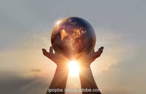 Eine Erdkugel von zwei Händen gehalten vor der Sonne - Symbol für Energiewende weltweit.