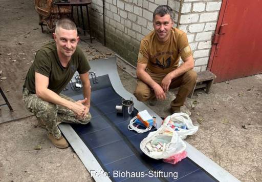 Im Bild zwei Männer mit einer der Solar-Dachbahnen, die für die Ukraine im Krieg gegen Russland sehr hilfreich sind.