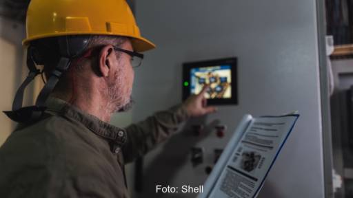 Mann mit gelbem Helm drückt auf Display an Heizungsanlage - Symbolbild für Bio-Heizöl von Shell.