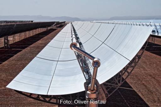 Ein Parabolrinnekollektor mit Rohrleitung in der Brennlinie auf rotem Gestein.