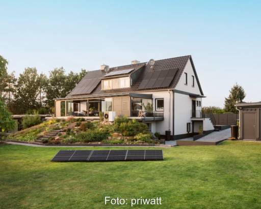 Auf dem Rasen vor einem Einfamilienhaus liegt eine Gruppe von Solarmodulen.