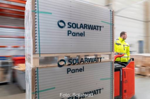 Verpackte Solarmodule von Solarwatt auf einer Palette im Lager mit Arbeitern.