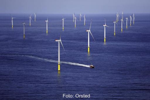 Ein Offshorewindpark bei ruhiger See. Ein Schiff manövriert hindurch.