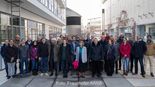 Dutzende Personen beim Gruppenfoto zwischen Institutsgebäuden.