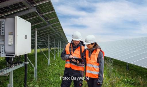Im Bild zwei Personen in einer Photovoltaik-Freiflächenanlage, zur Überwachung setzt Baywa re die Software Synaptiq ein.