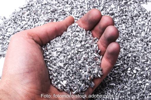 Silber- (oder Aluminium-)pellets in einer Hand. Symbolbild für Silber als wertvollen Rohstoff.