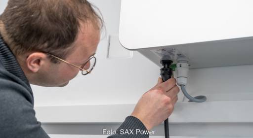 Im Bild ein Mann, der den PV-Speicher von SAX Power anschließt.