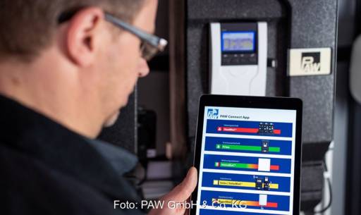 Im Bild ein Mann, der auf ein Tablett mit der PAW Connect App schaut.