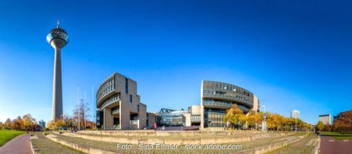 Ein Fernsehturm und eine modernes Gebäude vor blauem Himmel - Landtag in NRW berät über Landesentwicklungslpan.