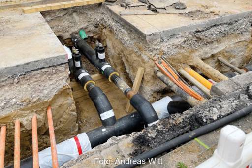Blick in eine Baugrube. Im Graben sind neben Fernwärmerohren vielfältige andere Versorgungsleitungen zu sehen. Symbolbild für das GEG und die kommunale Wärmeplanung.