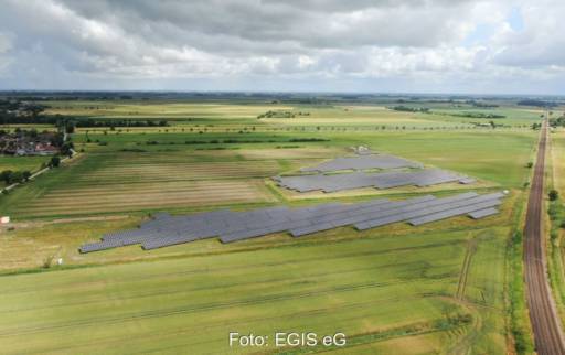 Luftbild eines Solarparks in Wiesen- und Ackerumfeld im Flachland.