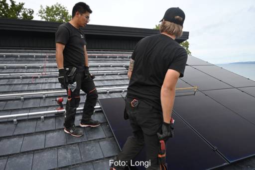 Zwei Installateure bei der Montage von Solarmodulen auf einem Schrägdach.