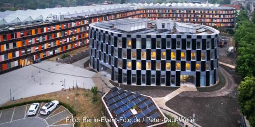 Im Bild ein rundes Gebäude mit Photovoltaik an der Fassade, der klimaneutrale Erweiterungsbau vom Umweltbundesamt, bei dem es sich um ein Plus-Energie-Gebäude handelt.