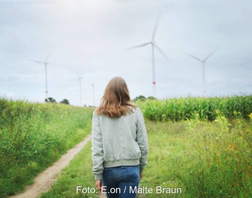 Eine Frau geht auf einem Feldweg auf einen Windpark zu - Symbol für regionalen Ökostrom von E.on