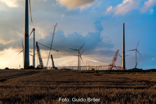 Kräne und bereits aufgestellte Windkraftmasten ragen in den Himmel: eine Baustelle für den Aufbau eines neuen Windparks