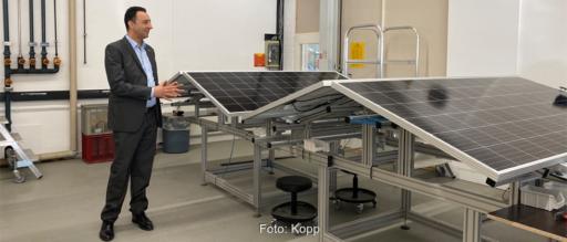 Ein Manager im Anzug vor zusammenklappbaren Solarmodulen.