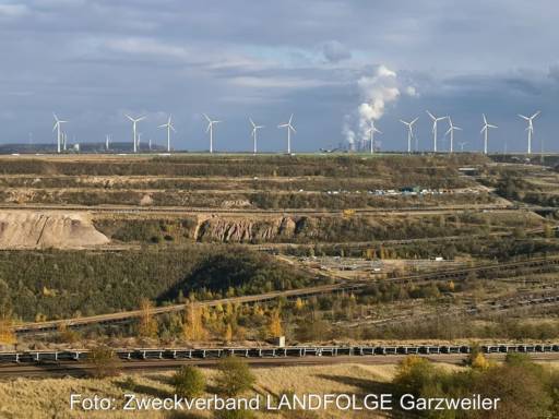 Hinter den Schluchten ehemaliger Braunkohleschächte erhebt sich eine Reihe Windkraftanlagen.