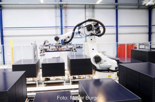 Ein Roboter stapelt schwarze Solarmodule.