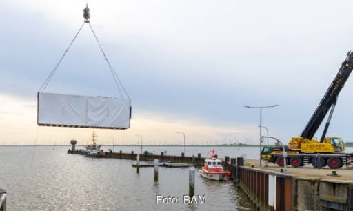 Im Bild ein Container am Haken über dem Wasser, der das Meerwasserlabor der BAM enthält.