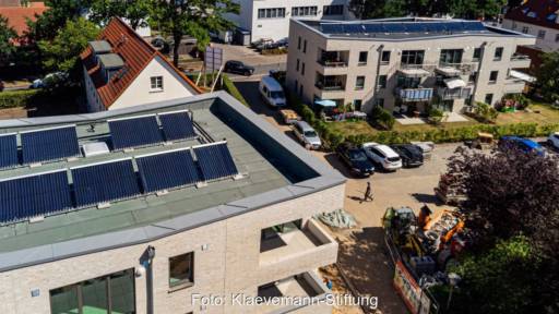 Luftbild zeigt Flachdächer von zwei dreistöckigen Wohnhäusern mit Röhrenkollektoren.