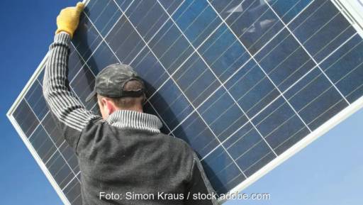 Im Bild ein Mann mit Solarmodul auf den Schultern als Symbol für den Photovoltaik-Bürokratieabbau.