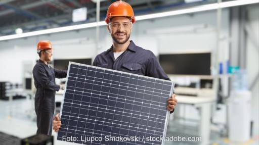 Im Bild ein Mann mit PV-Modul als Symbol für die Solarproduktion, die Plan-B Net Zero prüft.