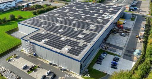 Luftbild einer Gewerbeimmobilie mit PV-Modulen auf dem Flachdach.