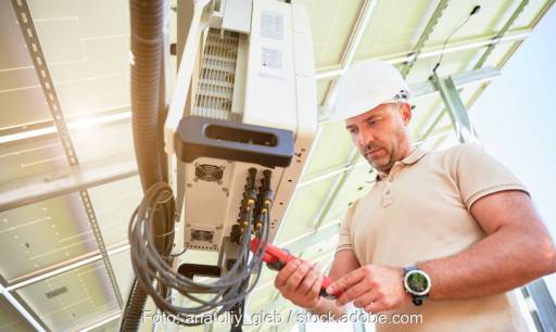Im Bild ein Mann, der einen Photovoltaik-Wechselrichter in einem Solarkraftwerk untersucht, von PV4Life soll Lebensdauer von Photovoltaik-Wechselrichtern verbessern.