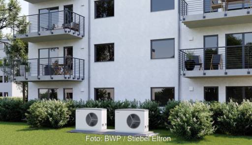 Im Bild ein Mehrfamilienhaus mit Wärmepumpe, neuer Praxis-Leitfaden für Wärmepumpen in Mehrfamilienhäuser der Dena.