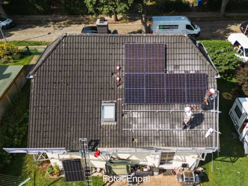 Luftaufnahme eines freistehenden Einfamilienhauses, auf dem gerade eine PV-Anlage montiert wird.