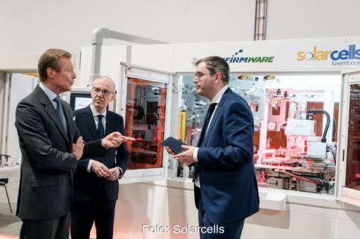 Drei Personen in Anzügen in einer Solarmodulfabrik.