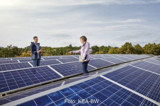 Zwei Personen inspizieren eine PV-Anlage auf einem Flachdach.