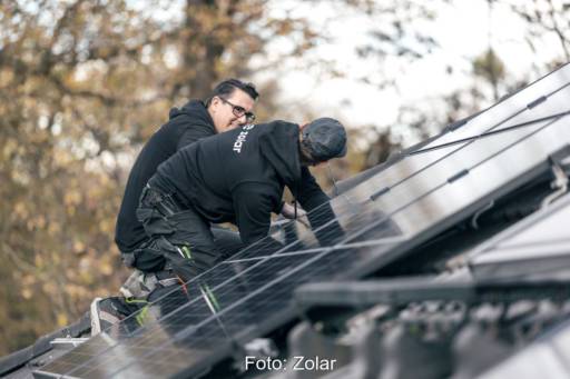Zwei Handwerker bei der Montage von Solarmodulen auf einem Satteldach.