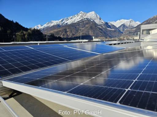 Photovoltaik-Dachanlage vor der Silhouette schneebedeckter Berge.